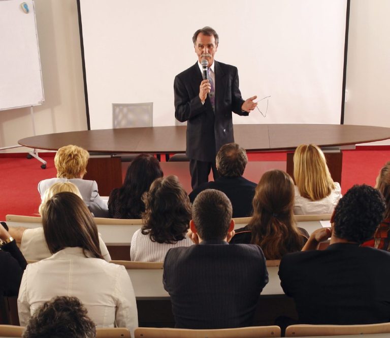 Businessman presenting to an audience at a corporate event with Transylvania Cakes' custom-crafted sweets served, embodying professional catering with a touch of elegance.